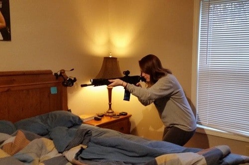 Woman Holding Rifle In Bedroom