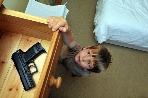 Little Boy Reaching For A Gun In Tray