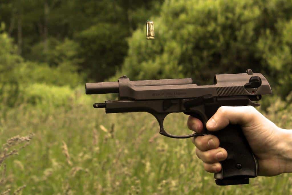 Semi automatic pistol held at shooting point within a grassy land