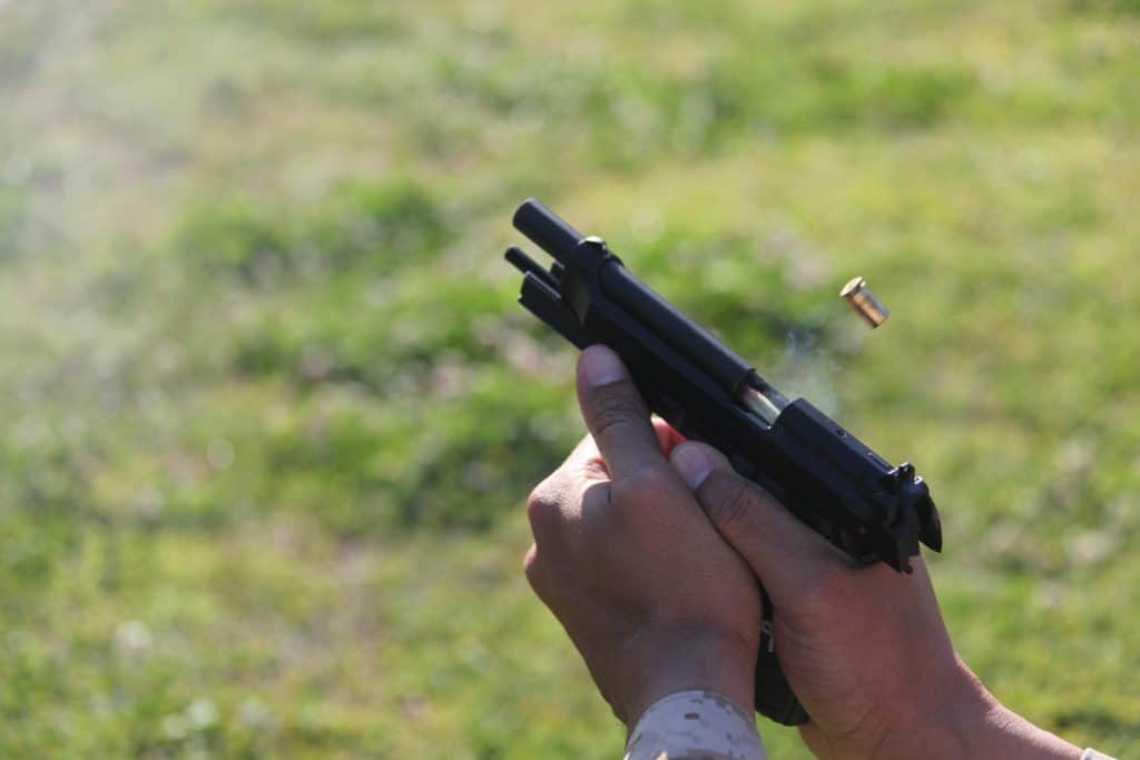 A man's hand holding a handgun while reloading it