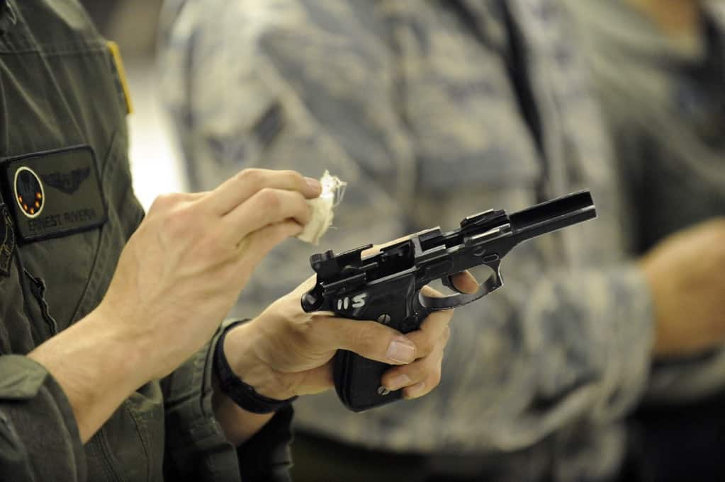 Man holding a handgun wiping it with a cotton pad