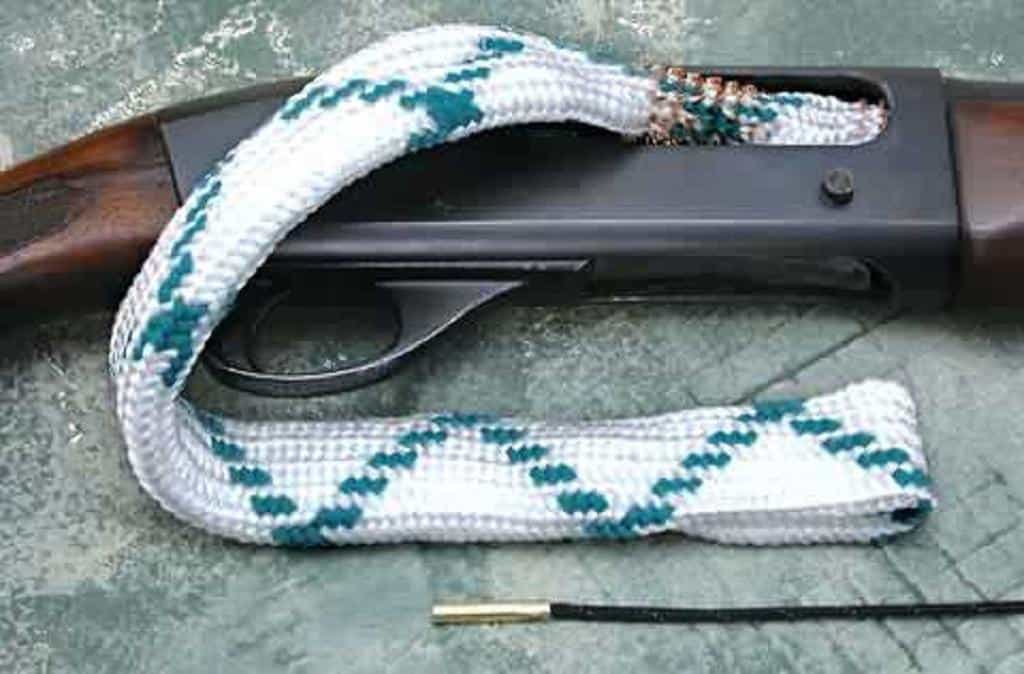 A white and green bore snake inserted through a rifle