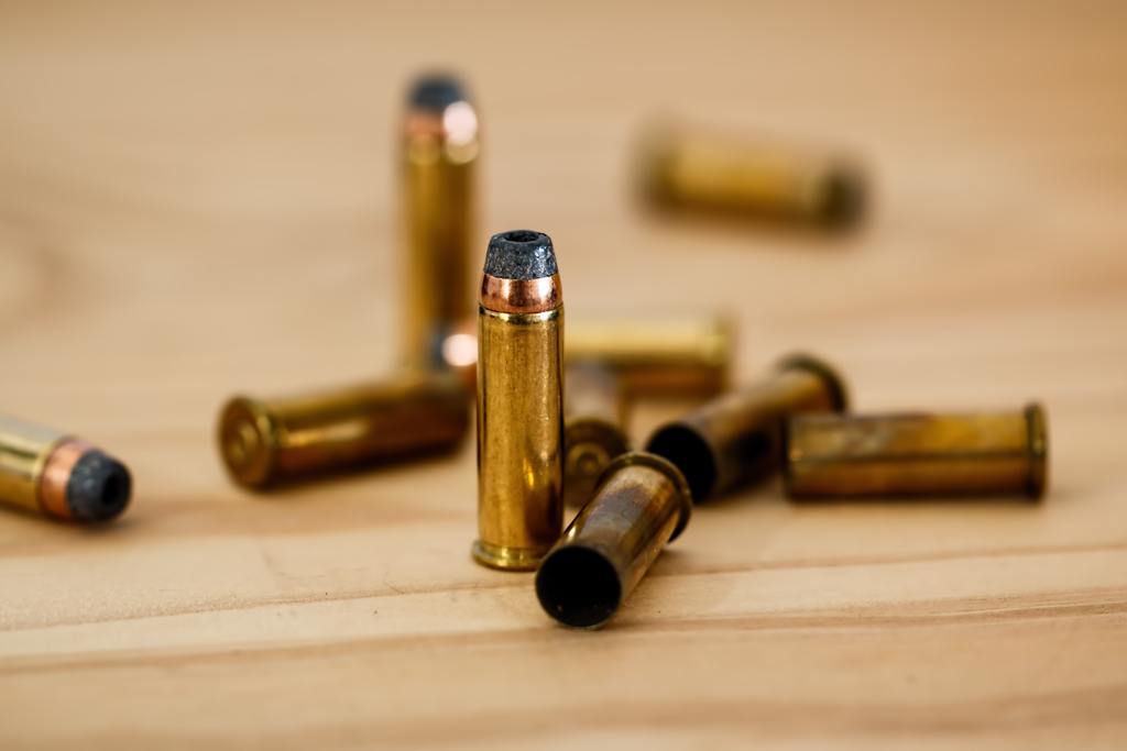 Gold ammunition standing up beside other that are laid on the counter