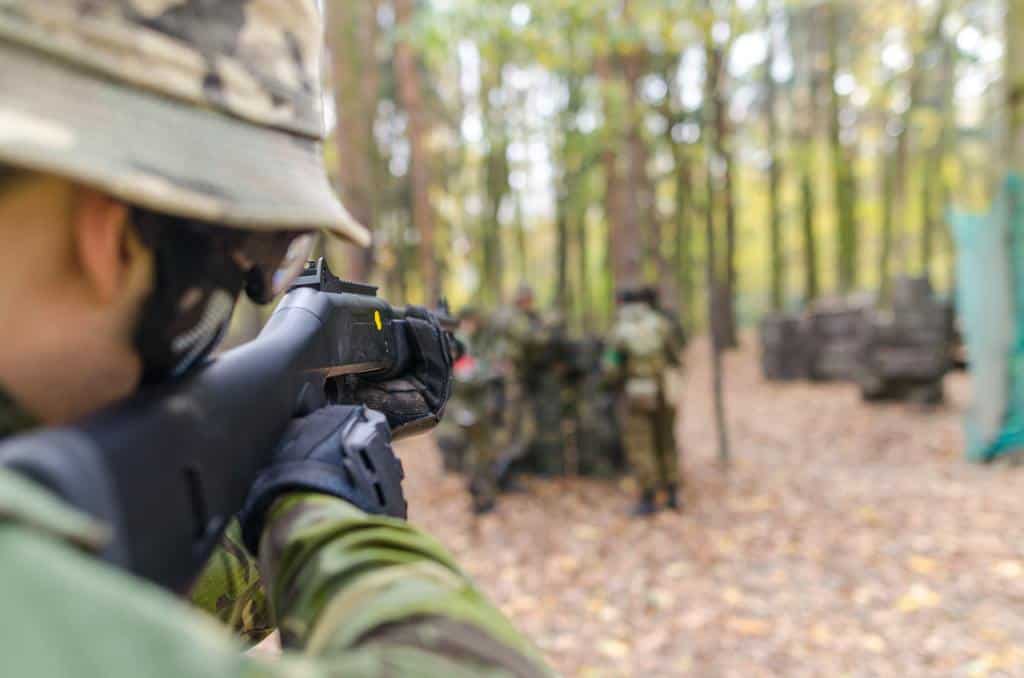 Soldier uses a rifle to aim at other soldiers in the forest