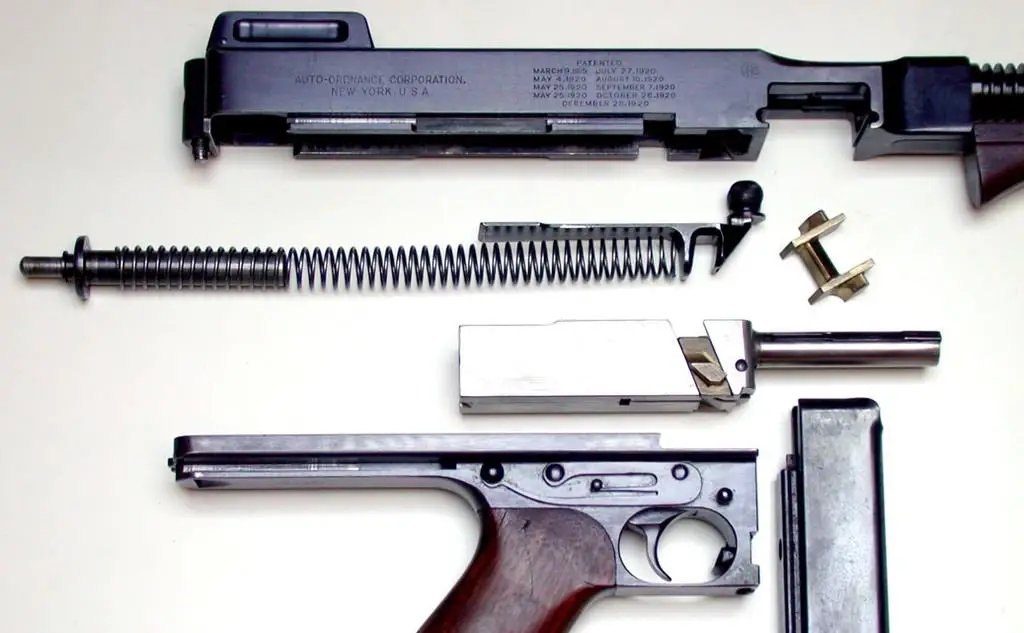 A handgun taken apart with all of its pieces laid on a white surface