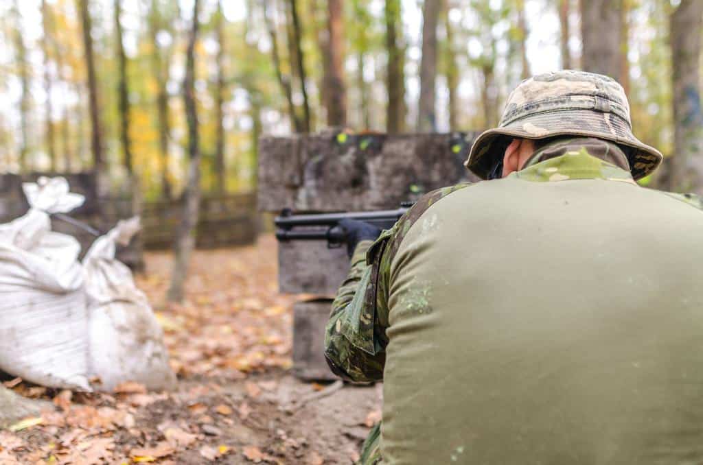 A man with  his back turned aiming the rifle for hunting