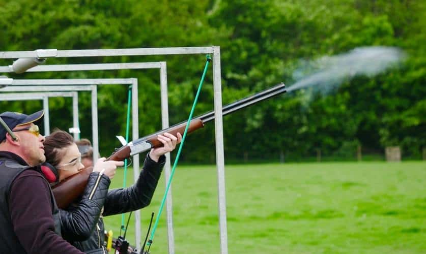 Man coaching a woman on how to fire a shotgun at a gun range