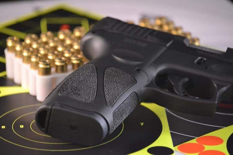 Gun placed on a cleaning mat with a box of bullets beside it