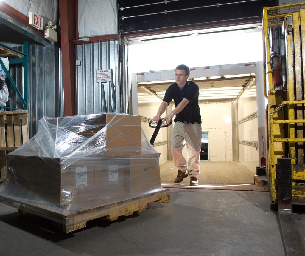 Man unloading pallet from truck into warehouse