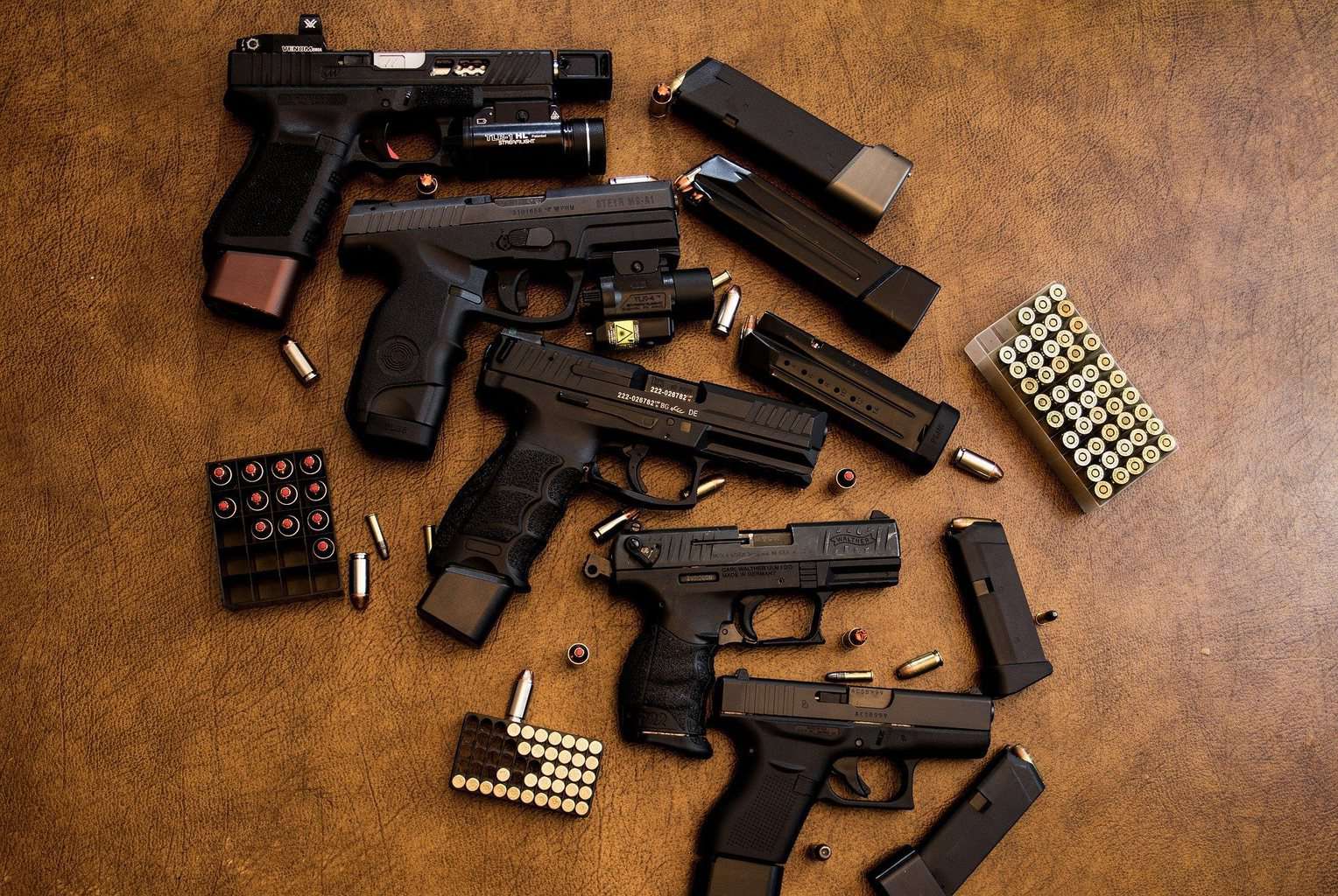 A variety of handguns with boxes of bullets