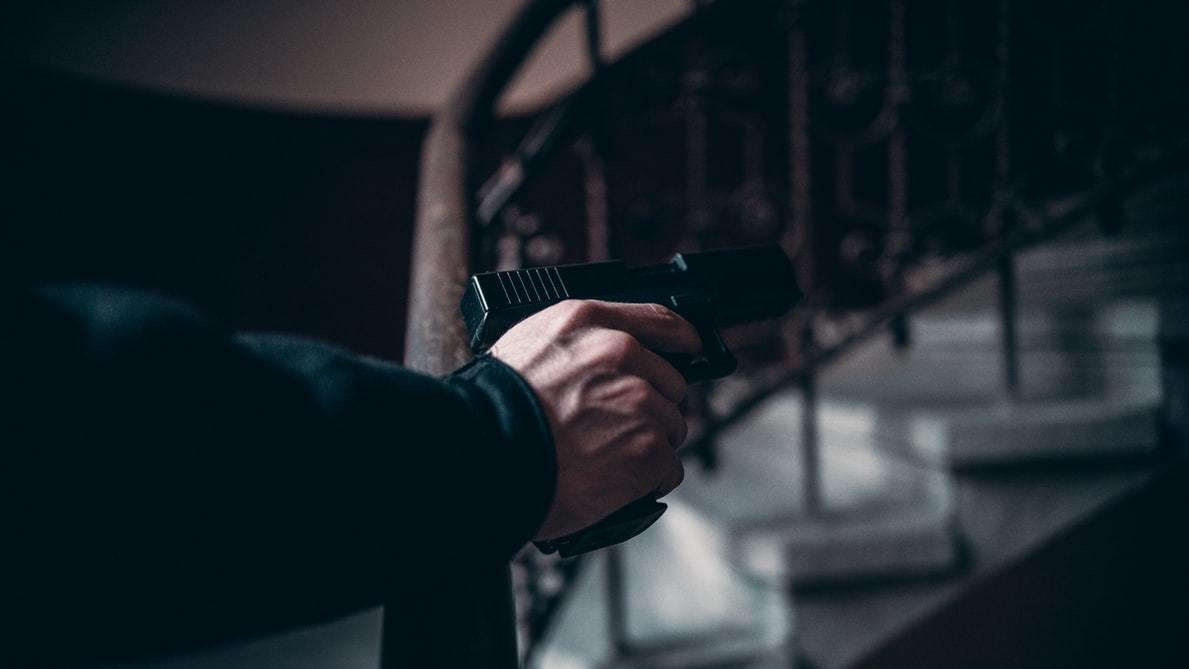 Man pointing a gun near the stairs