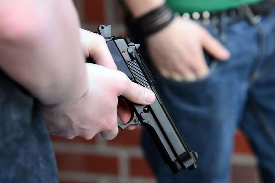 A man carrying handgun beside another person