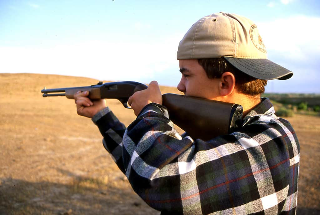 Man holding a gun at an outdoor gun range