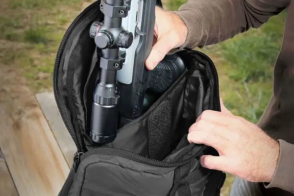 Man storing his rifle on his range backpack