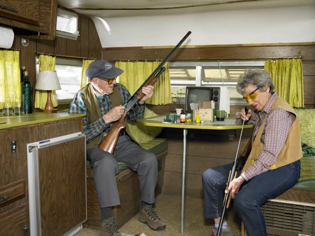 An elderly couple cleaning their rifles