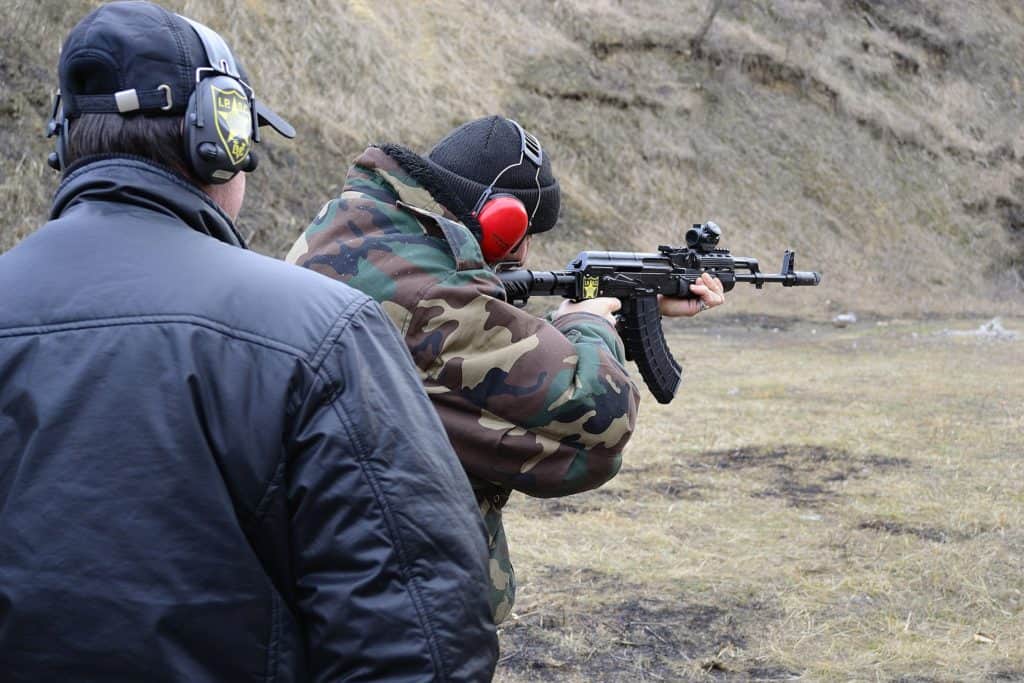 Man doing target shooting outdoors with an instructor 