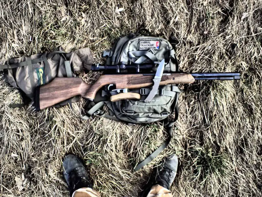 Rifle on top of a backpack lying on the grass