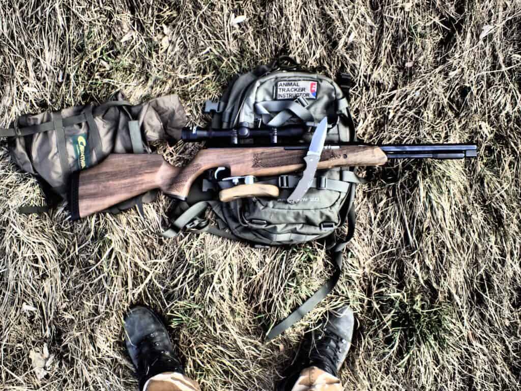 Rifle on top of a backpack lying on the grass