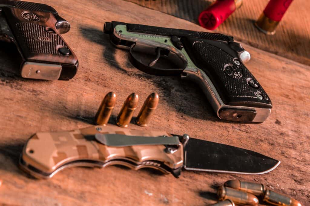 Bullets, knife and handguns in a table