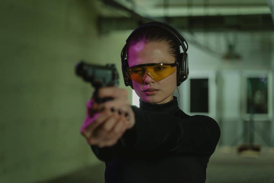 Woman aiming a gun while in a shooting range