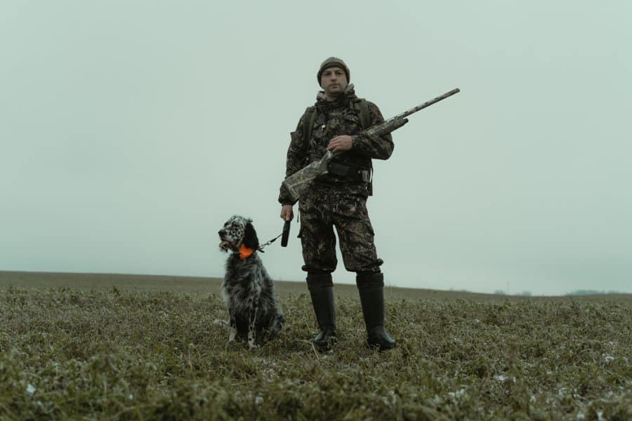 Man holding his shotgun and his dog, wondering if he needs a gun permit to shoot at a gun range in Maine