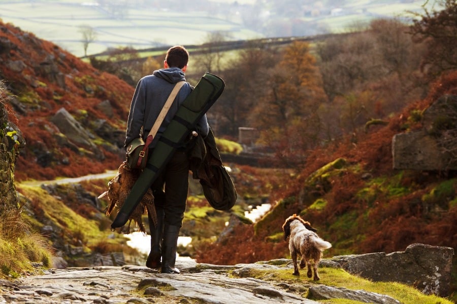 Man walking with his dog and rifle bag, not needing a gun permit to shoot at a gun range in Utah