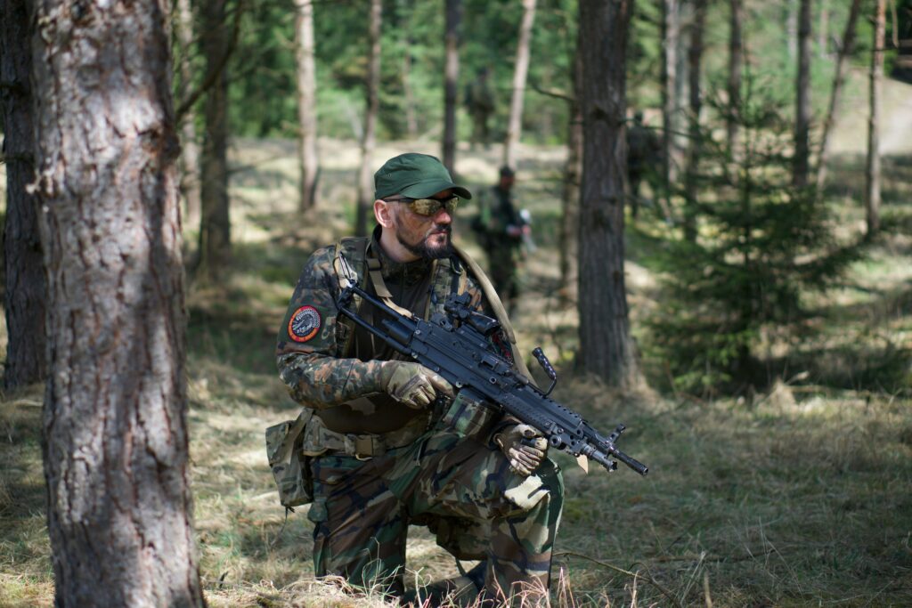 a kneeling man in black and green camo