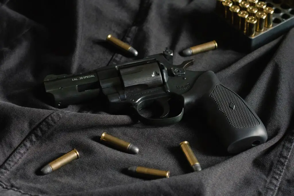 A black revolver with bullets on black cloth