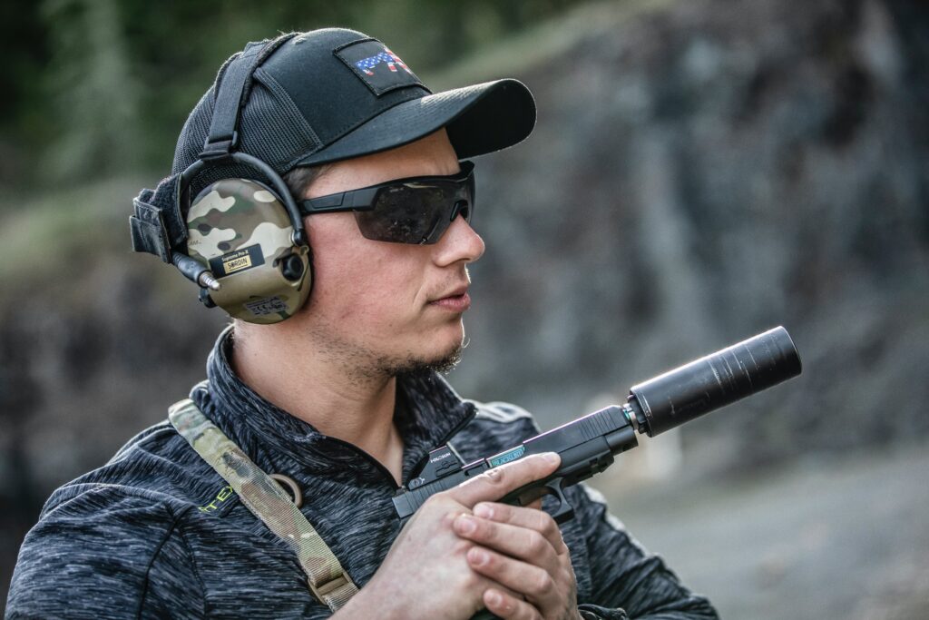 A man with black sunglasses and silenced gun