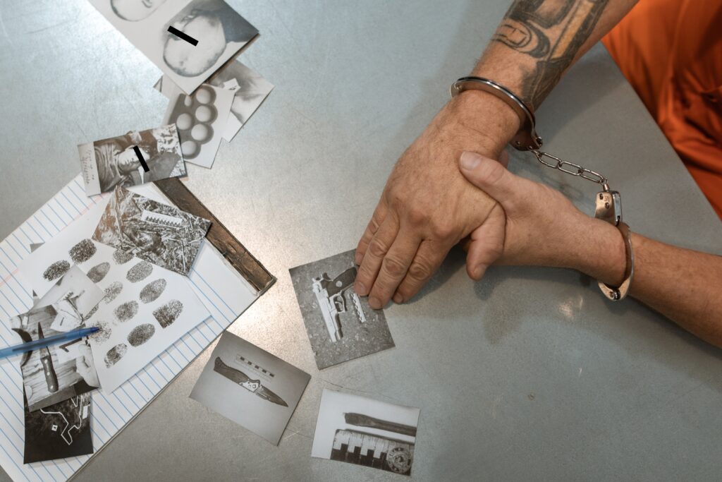 person handcuffed with pictures of weapons on the table