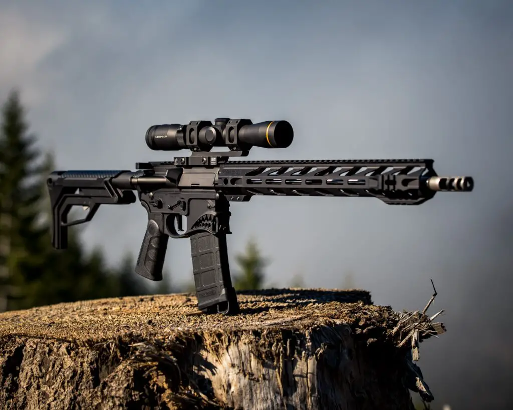 automatic black rifle on top of a log
