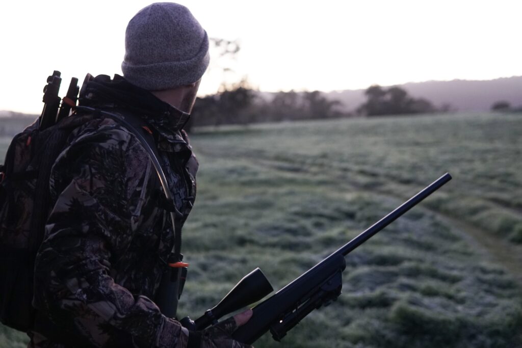 man holding a rifle looking out into the landscape