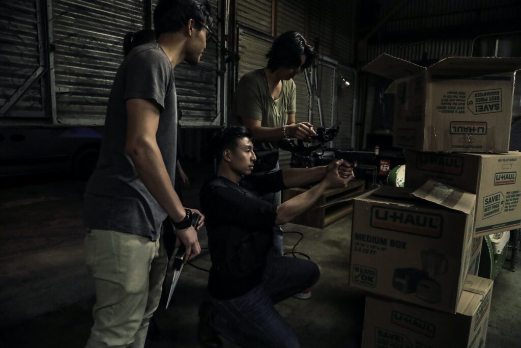 three people in a warehouse holding guns