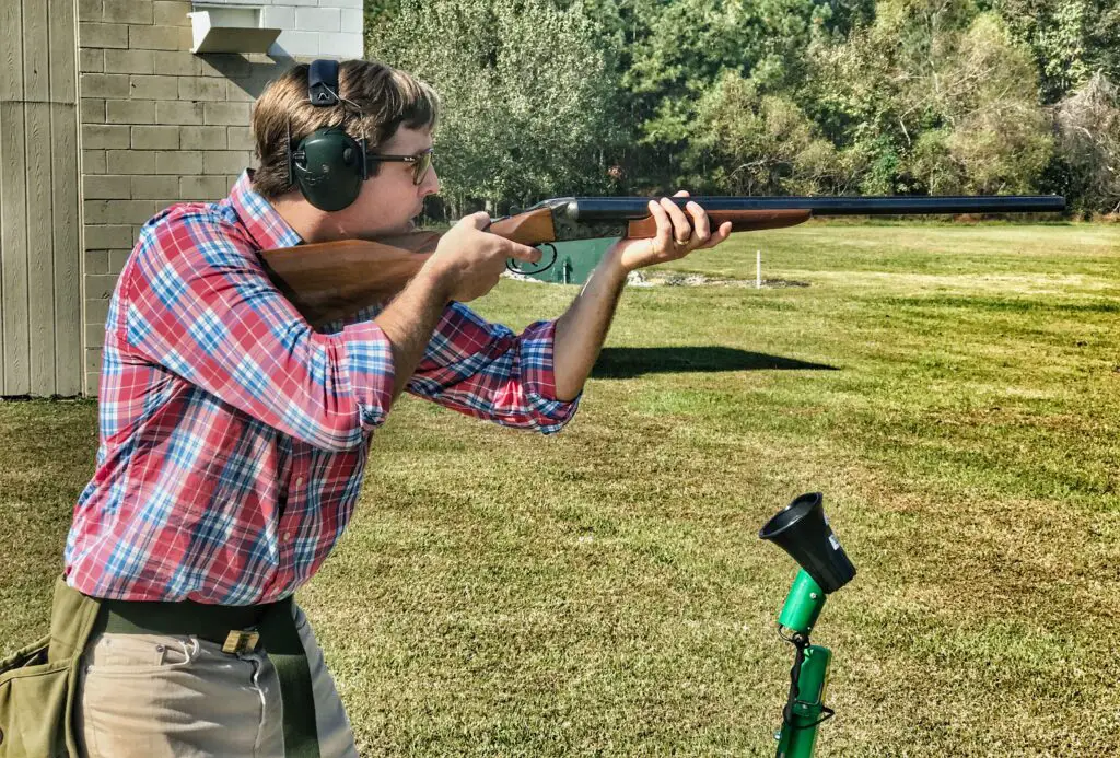 guy in red and blue plaid polo shooting a rifle