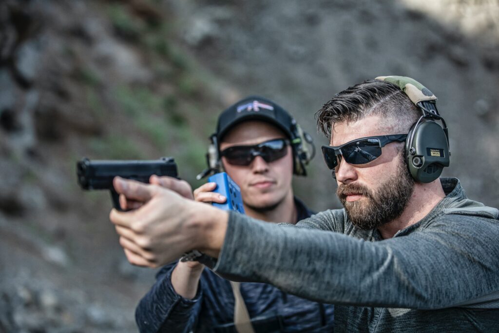 man in gray long sleeves holding a pistol