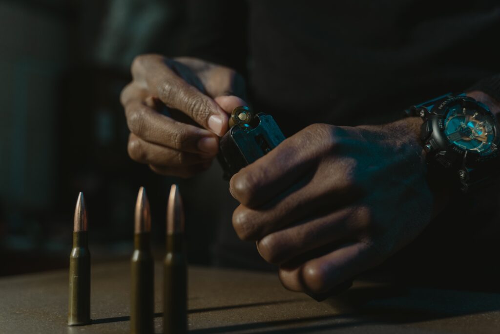 Hand reloading a gun magazine and bullets on a desk