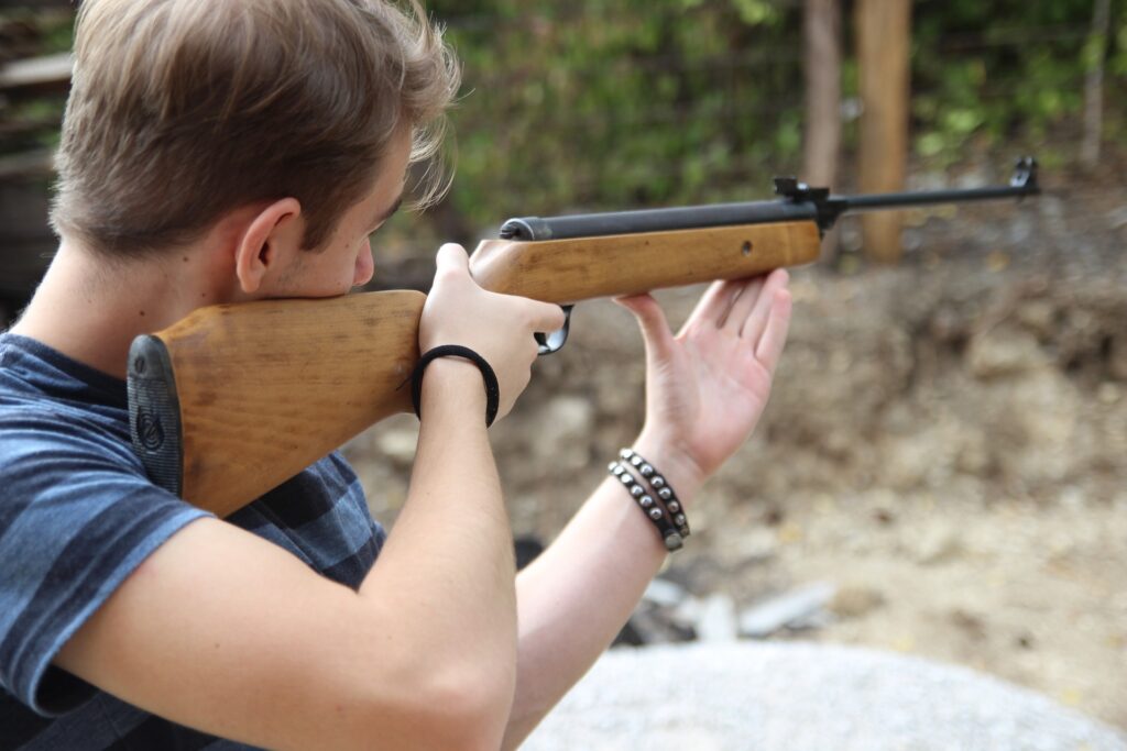 Guy in blue shirt holding a brown rifle