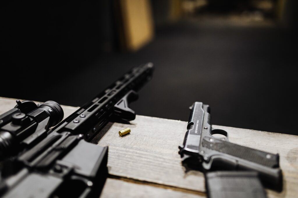 Semi automatic pistol and a rifle on wooden tableen desk