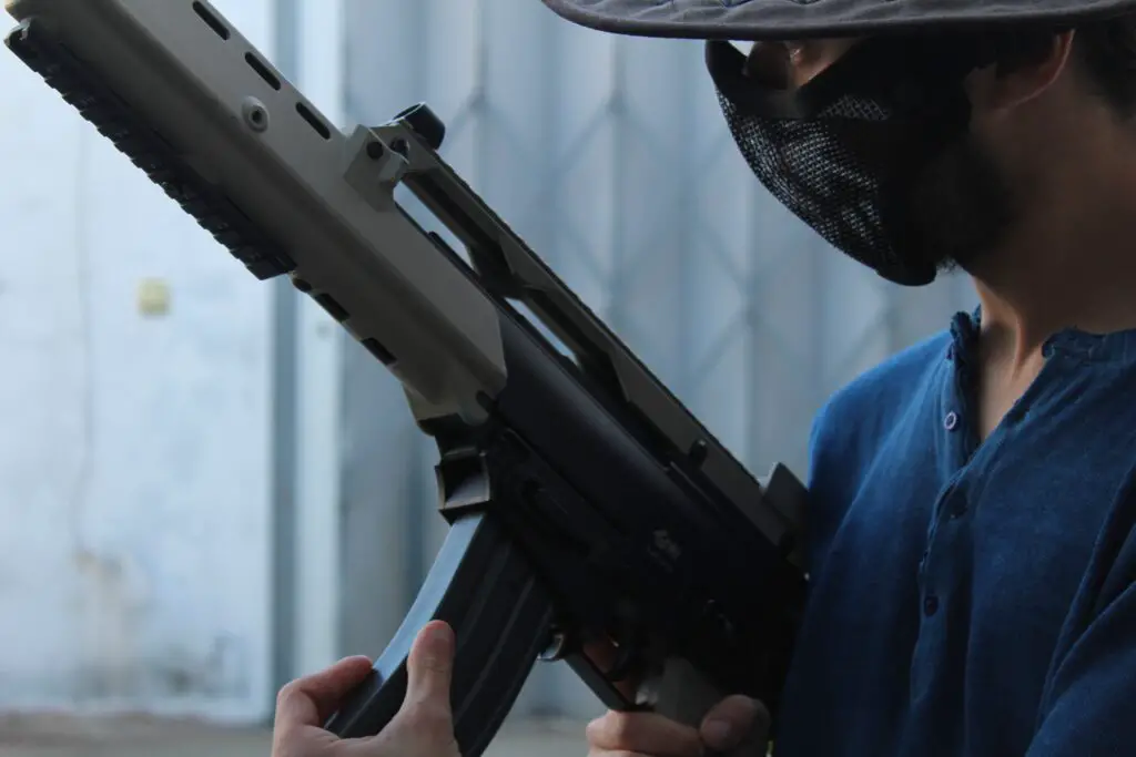 A person with protective equipment holding an assault rifle