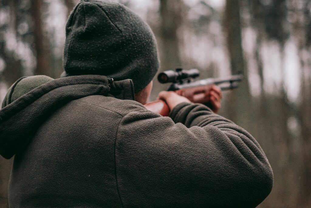 Rear view of a person aiming a sniper hunting rifle