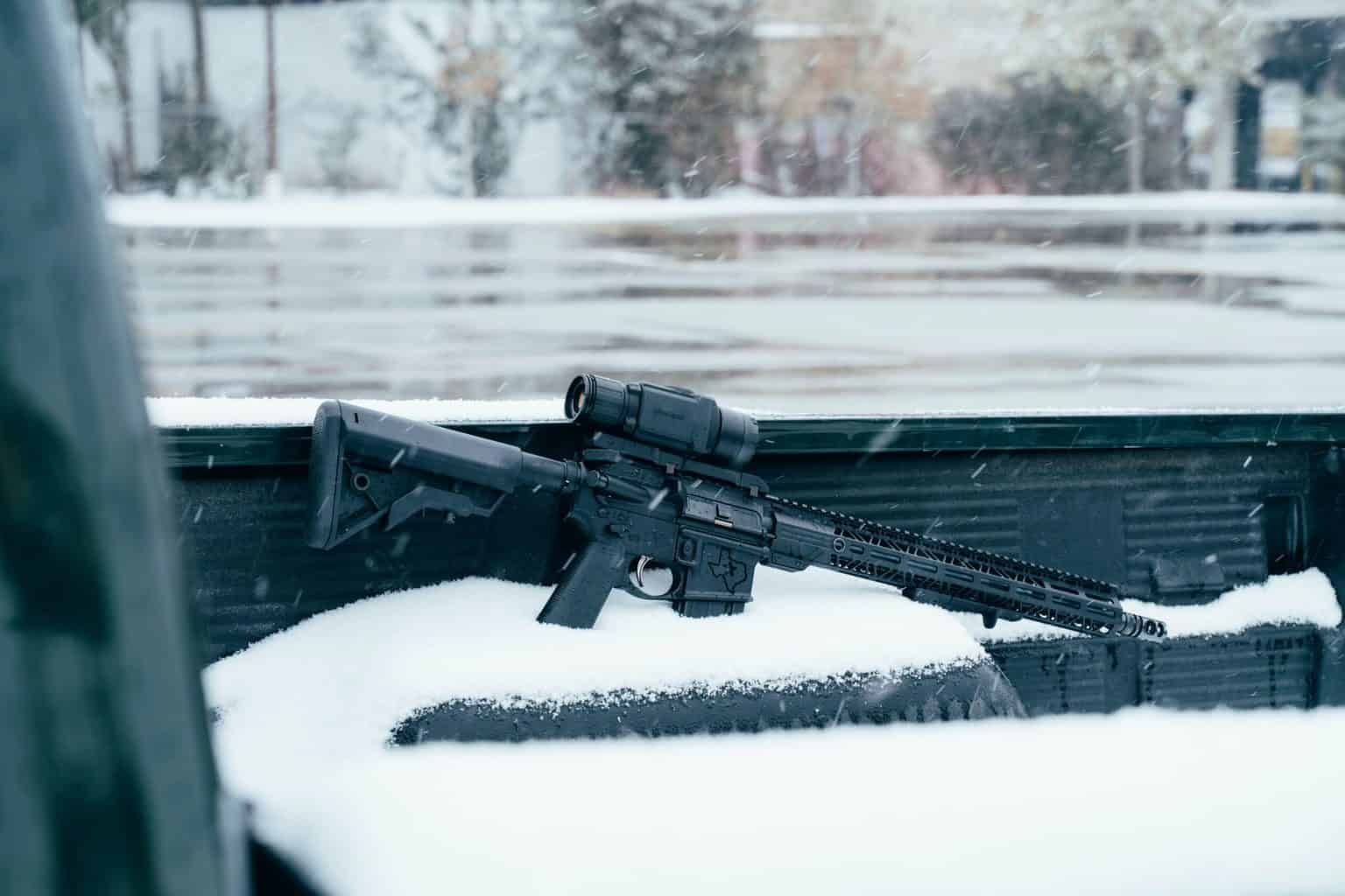 A firearm partially covered with snow in the ground
