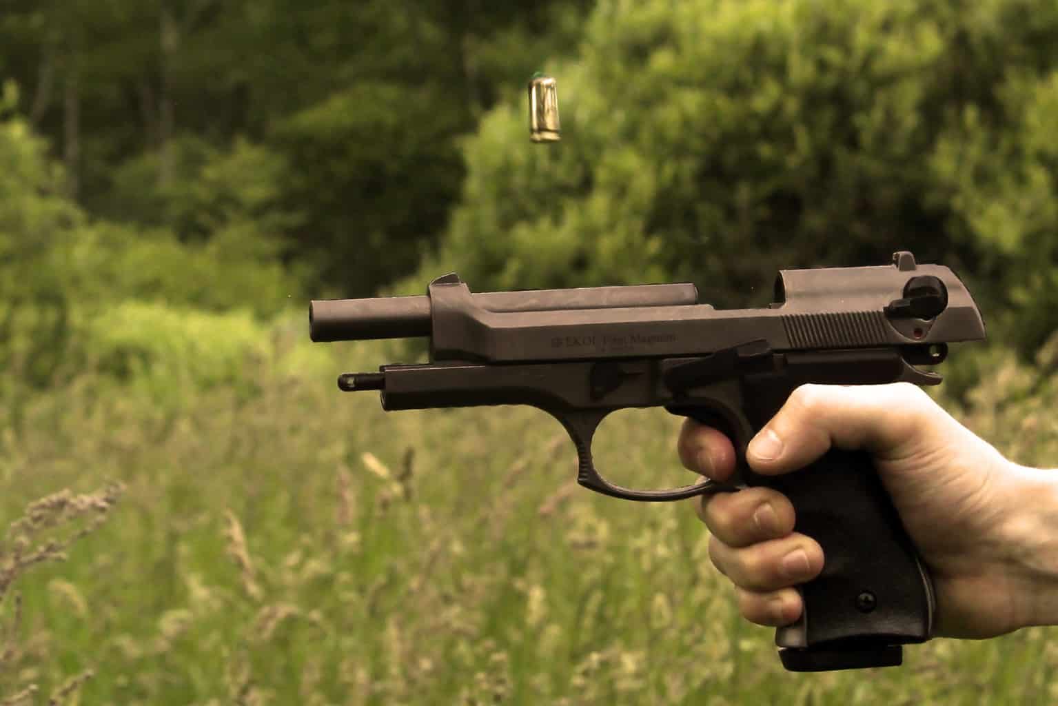 A pistol being shot with a flying bullet