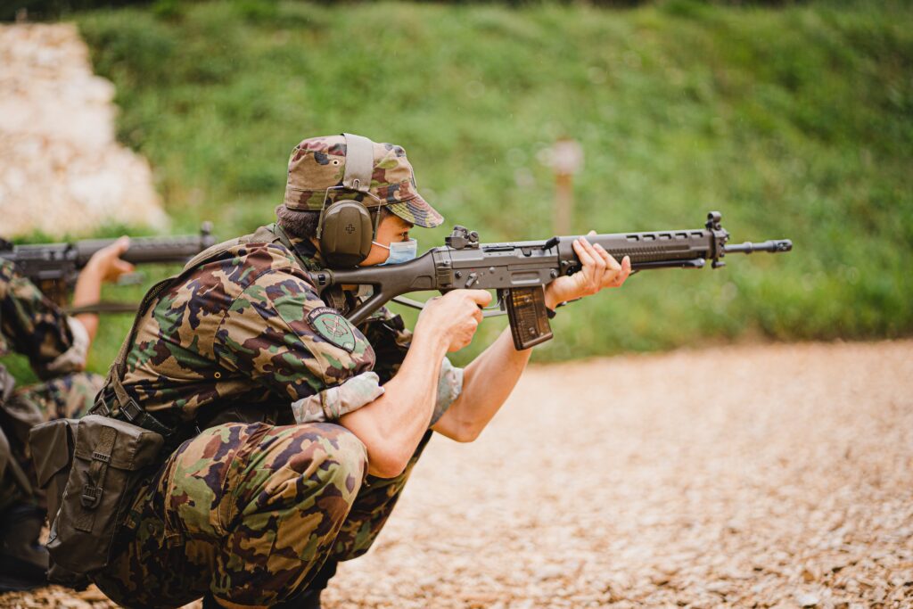 A person wearing soldier equipment while aiming a gun