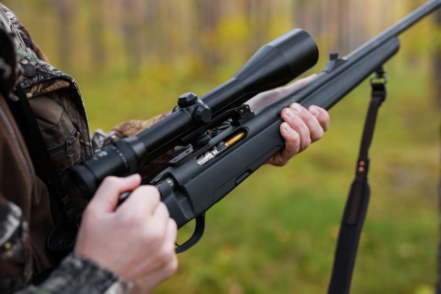 Hunter loading his gun equipped with a Nikon Buckmaster scope