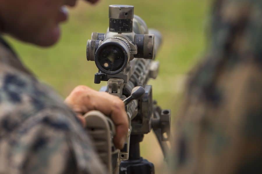 Man holding onto a rifle with a mounted scope