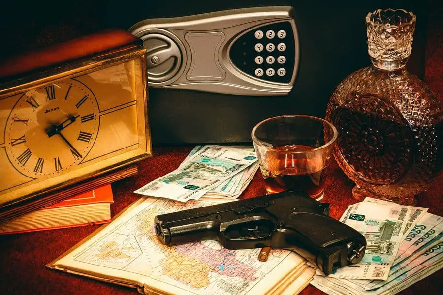 Gun on top of a pile of a map, paper bills and near a gun safe and clock