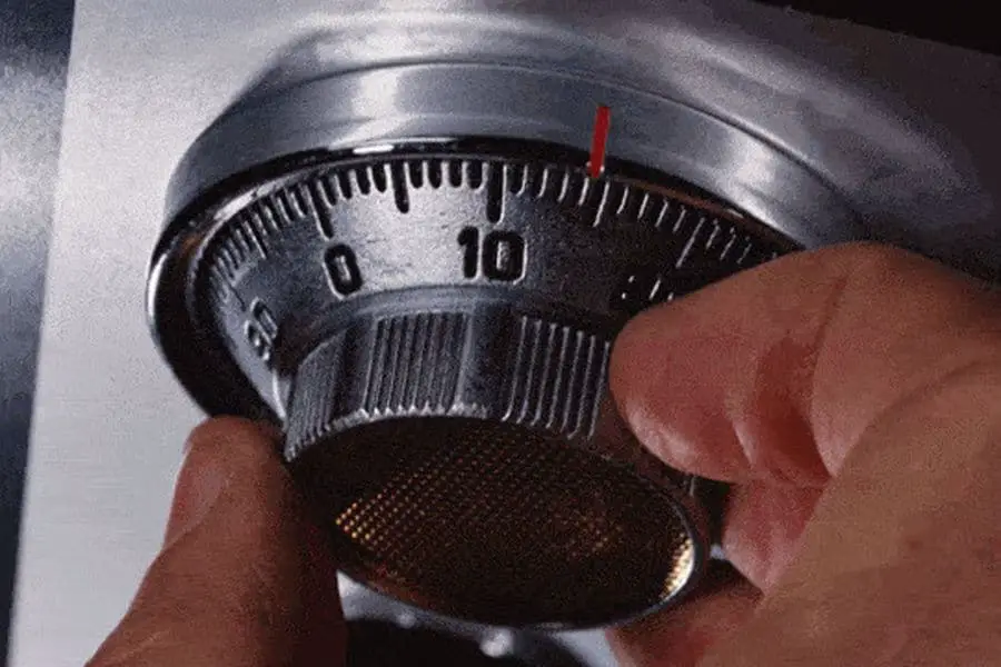 Hand trying to open a combination lock