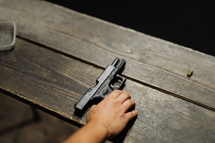 A hand placing a gun on a wooden plank