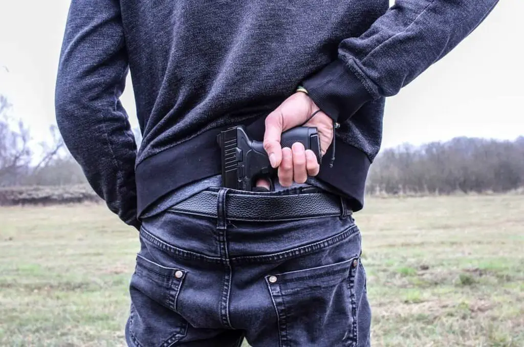 Young man placing a gun inside the back of his jeans