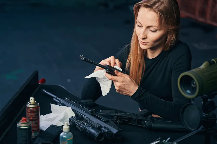 Female shooter wiping the gun parts with CLP gun cleaner